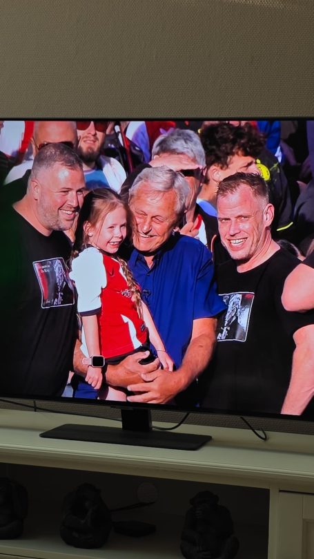 Een groep mannen met een meisje, allemaal in blije houding en lachend.