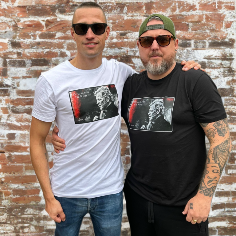 Twee mannen poseren voor een bakstenen muur, gekleed in T-shirts met afbeeldingen.