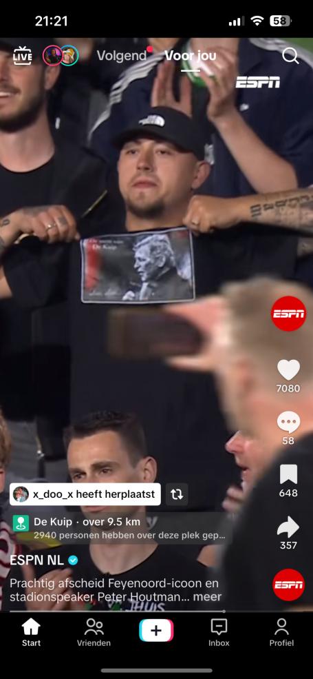 Man in een zwart T-shirt houdt een foto omhoog, omringd door enthousiaste mensen.