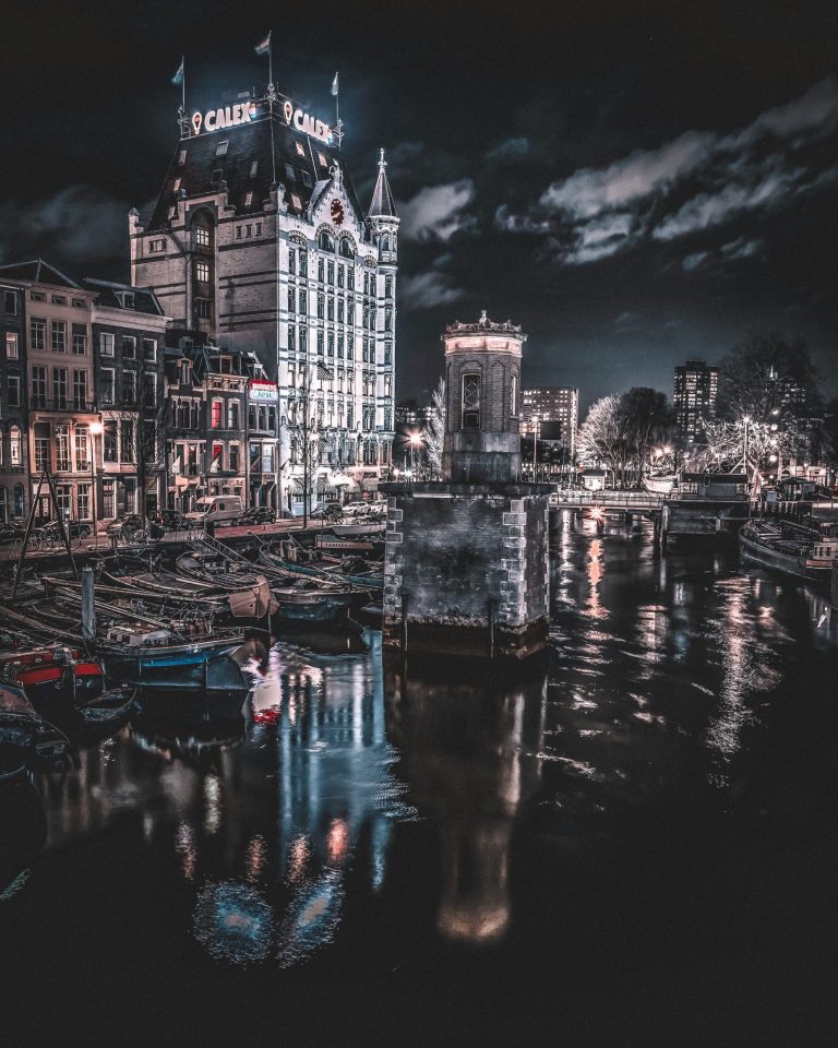 Stadszicht met een verlichte gebouwen en reflecties in het water bij nacht.